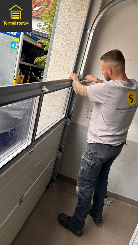Fachberater von Tormeister24 prüft ein geöffnetes Sektionaltor in einer Garage