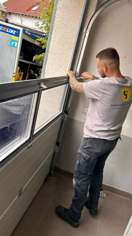 Fachberater von Tormeister24 prüft ein geöffnetes Sektionaltor in einer Garage